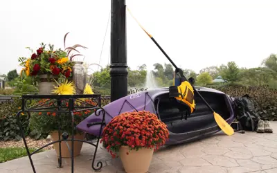 Kayak leaning up against light post with pond behind it