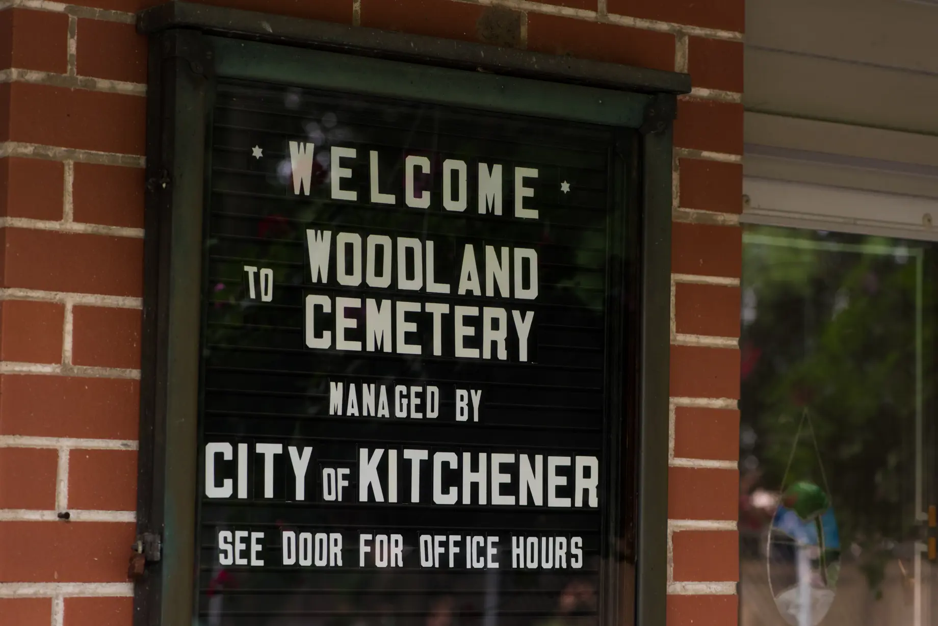 Sign on wall that says Welcome to Woodland Cemetery