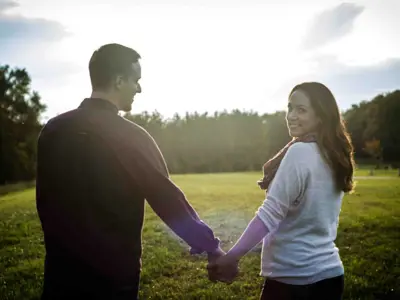 couple holding hands and looking over their shoulders at camera